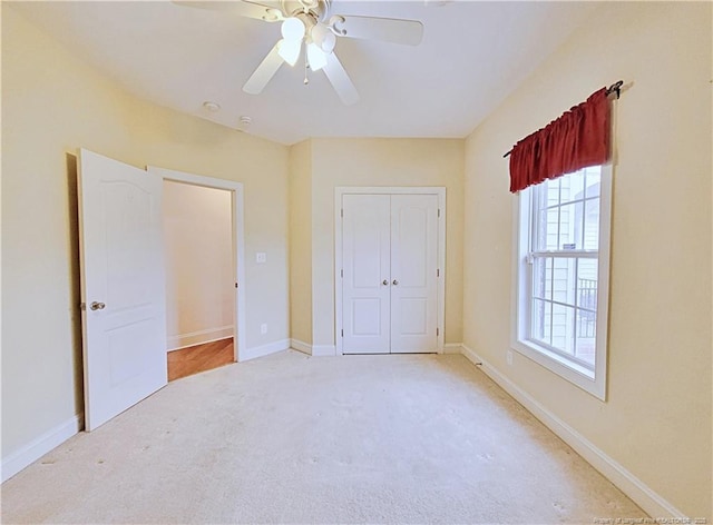 unfurnished bedroom featuring a closet, light carpet, ceiling fan, and baseboards