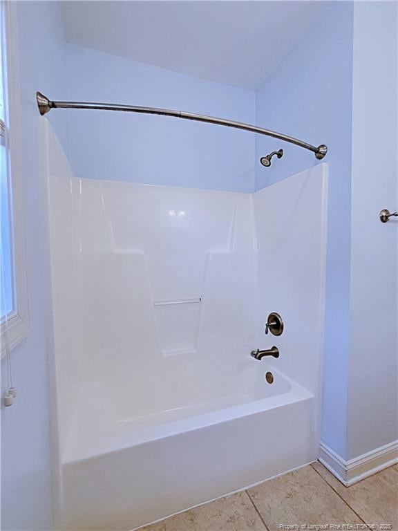 bathroom featuring  shower combination, tile patterned flooring, and baseboards