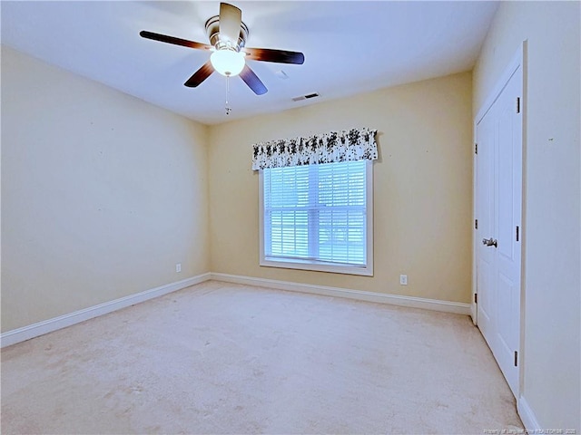 unfurnished room with light carpet, a ceiling fan, visible vents, and baseboards