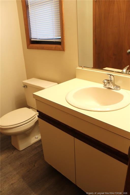 bathroom with toilet, wood finished floors, and vanity