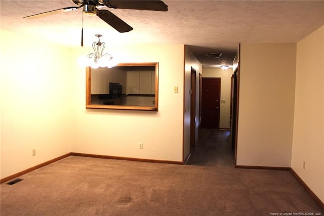 unfurnished room with visible vents, dark carpet, and baseboards