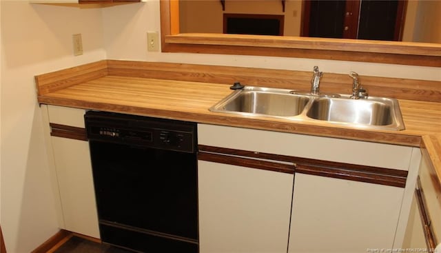 kitchen with butcher block countertops, black dishwasher, white cabinetry, and a sink