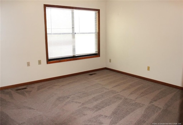 unfurnished room with carpet, visible vents, and baseboards