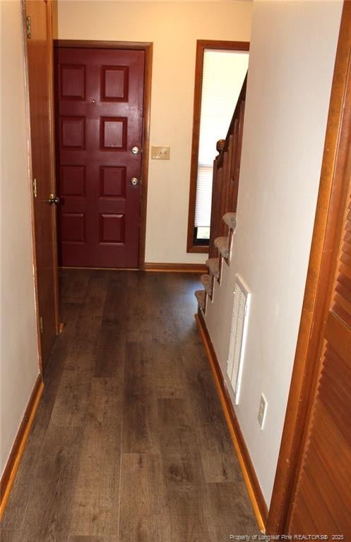 hallway featuring dark wood-style floors, stairway, visible vents, and baseboards