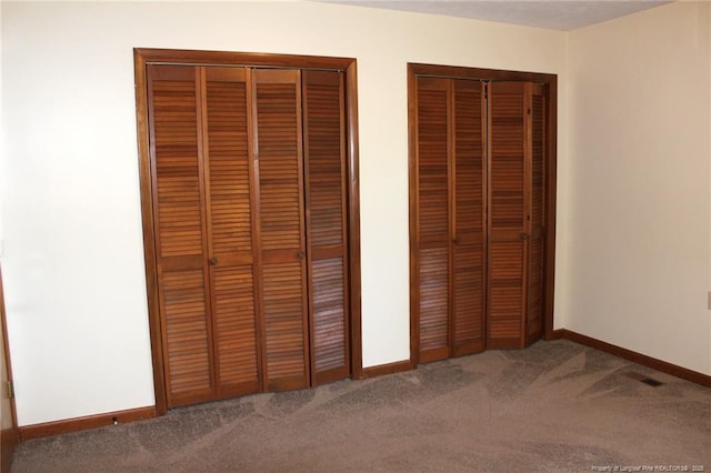 interior space with carpet floors, visible vents, baseboards, and two closets