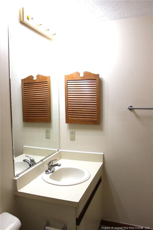 bathroom featuring toilet, a textured ceiling, and vanity