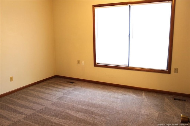 unfurnished room featuring carpet, visible vents, and baseboards