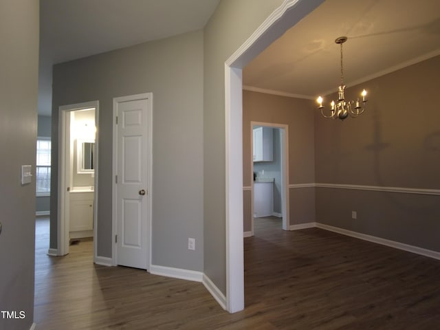 unfurnished dining area with baseboards, an inviting chandelier, dark wood-style flooring, and crown molding