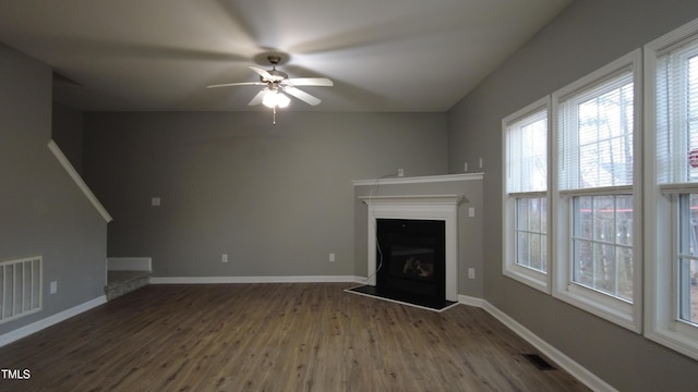 unfurnished living room featuring visible vents, baseboards, a ceiling fan, and wood finished floors