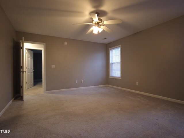 empty room featuring light colored carpet, baseboards, and ceiling fan