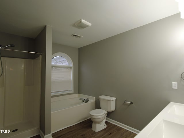 bathroom with visible vents, toilet, wood finished floors, a bath, and a shower