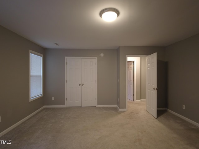 unfurnished bedroom with a closet, baseboards, and light colored carpet