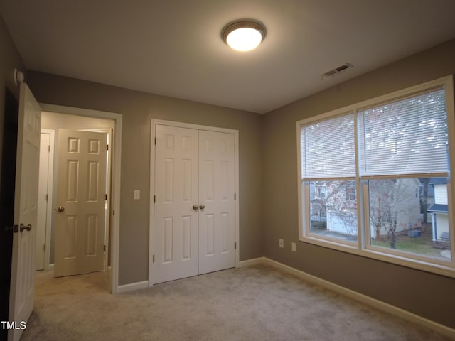 unfurnished bedroom with light colored carpet, visible vents, a closet, and baseboards