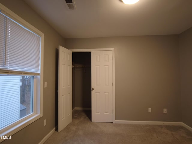 unfurnished bedroom featuring baseboards, visible vents, and light carpet