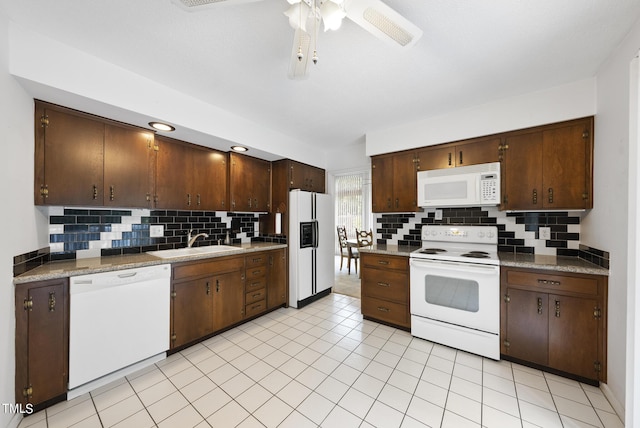 kitchen with a ceiling fan, a sink, tasteful backsplash, white appliances, and dark brown cabinetry