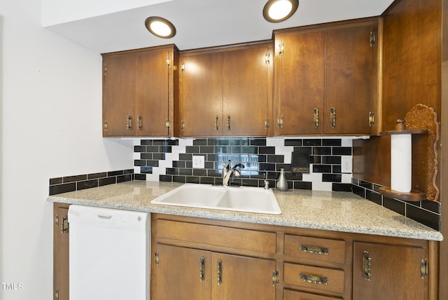 kitchen featuring a sink, brown cabinets, tasteful backsplash, and white dishwasher