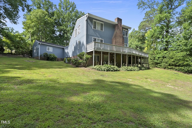 back of property with a deck, a chimney, and a yard