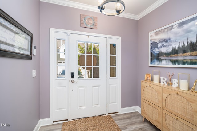 foyer entrance with crown molding, baseboards, and wood finished floors