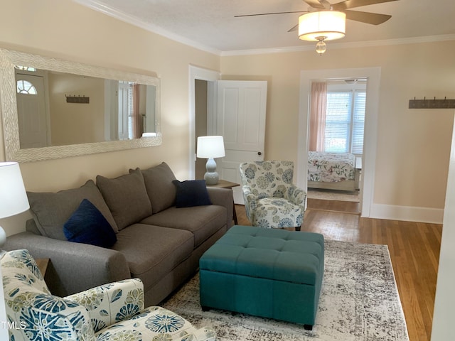 living room with baseboards, a ceiling fan, wood finished floors, and crown molding