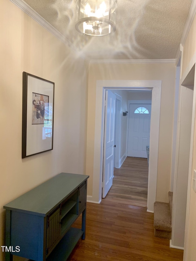 hallway featuring a notable chandelier, dark wood-type flooring, a textured ceiling, crown molding, and stairs