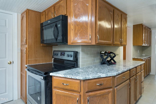 kitchen with light stone counters, brown cabinets, stainless steel electric stove, and black microwave