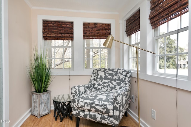 living area with a wealth of natural light, crown molding, baseboards, and wood finished floors