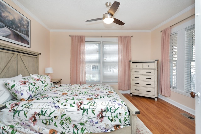 bedroom with visible vents, multiple windows, wood finished floors, and ornamental molding