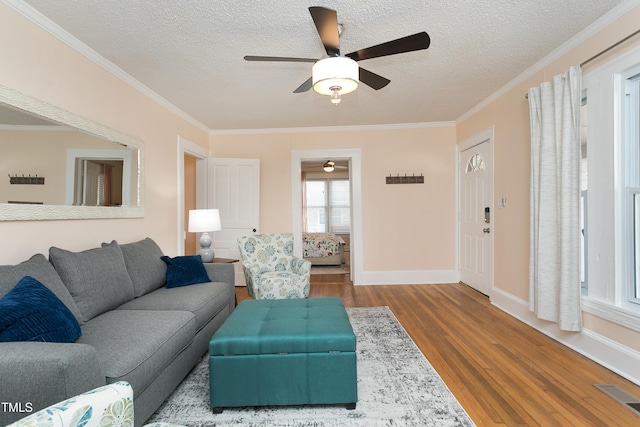 living room featuring visible vents, ornamental molding, a ceiling fan, and wood finished floors