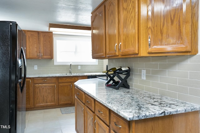 kitchen featuring black fridge, brown cabinets, and a sink