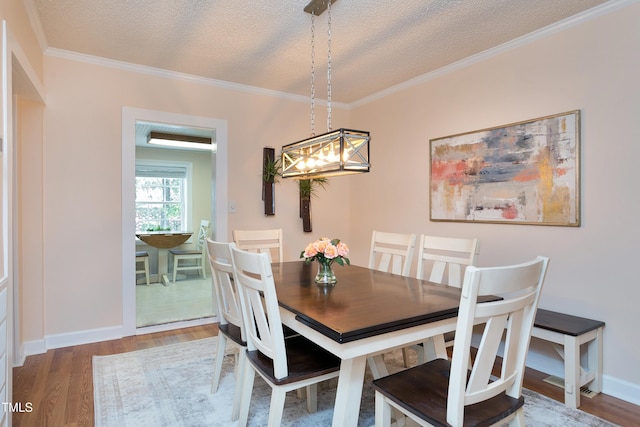 dining area featuring baseboards, ornamental molding, wood finished floors, a notable chandelier, and a textured ceiling