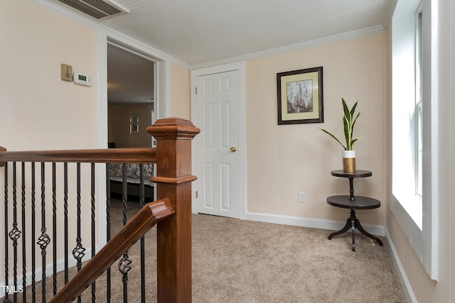 hallway featuring an upstairs landing, visible vents, baseboards, and carpet floors