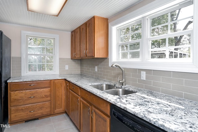 kitchen featuring light tile patterned floors, brown cabinetry, light stone countertops, a sink, and decorative backsplash