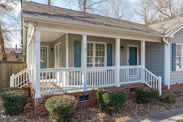 doorway to property featuring crawl space, a porch, and roof with shingles