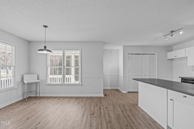 unfurnished dining area with a textured ceiling, baseboards, and wood finished floors