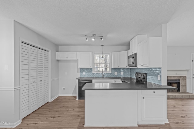 kitchen featuring dishwashing machine, a peninsula, stainless steel electric stove, black microwave, and a sink