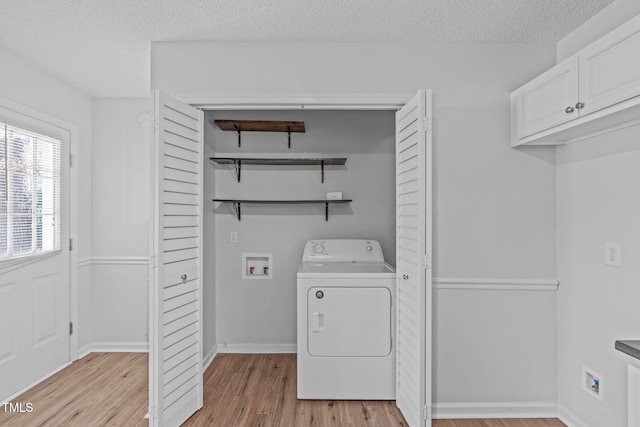 washroom featuring light wood finished floors, laundry area, washer / clothes dryer, and a textured ceiling