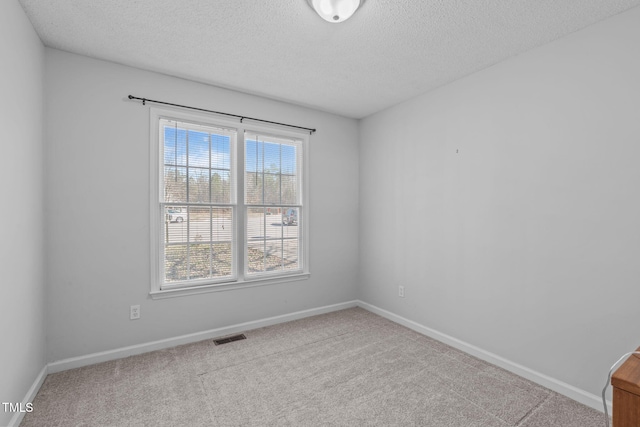 carpeted empty room with baseboards, visible vents, and a textured ceiling