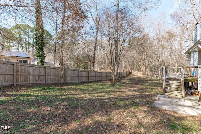 view of yard with a fenced backyard, a wooden deck, and stairs