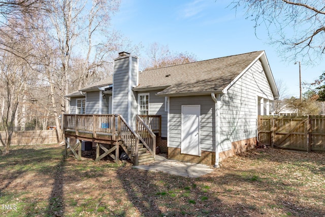 back of property featuring cooling unit, a shingled roof, fence, a wooden deck, and a chimney