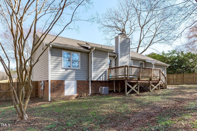 back of property with a chimney, fence, a deck, cooling unit, and brick siding