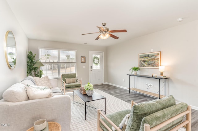 living room with ceiling fan, baseboards, and wood finished floors