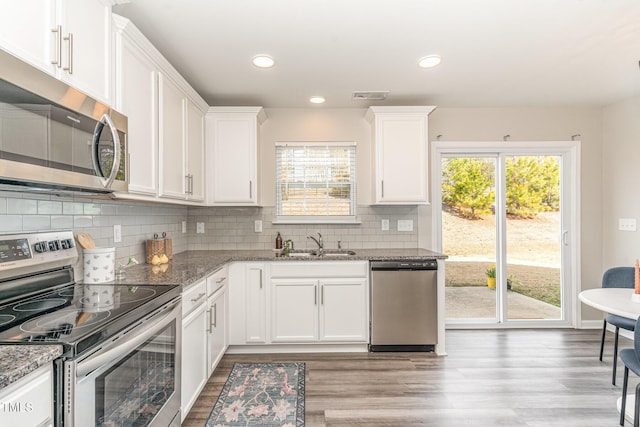 kitchen featuring white cabinets, light stone countertops, stainless steel appliances, and a sink