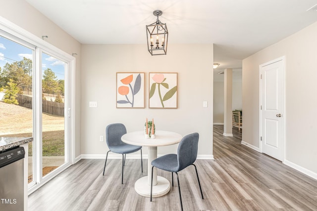 dining area with light wood-type flooring, baseboards, and an inviting chandelier