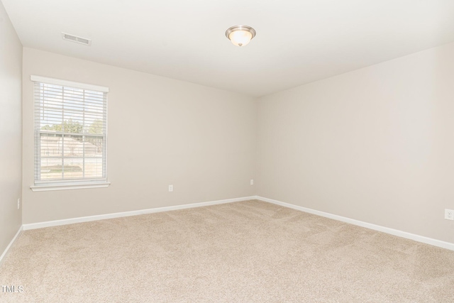 empty room with carpet, visible vents, and baseboards