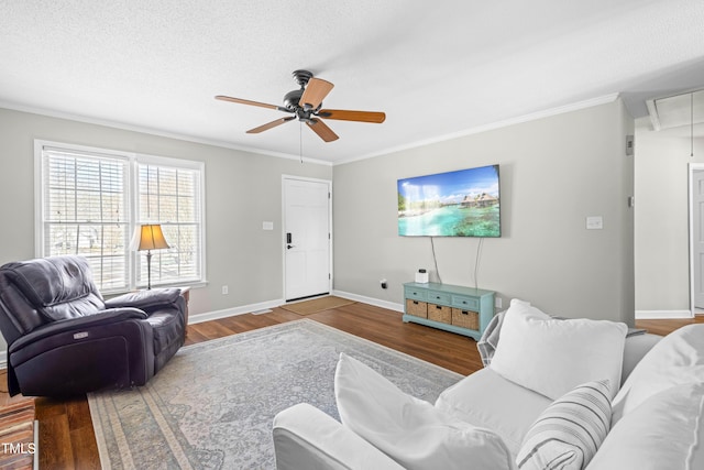 living area with attic access, ornamental molding, a textured ceiling, wood finished floors, and baseboards