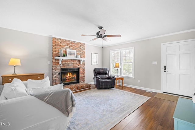 living room featuring dark wood-style floors, a fireplace, crown molding, a ceiling fan, and baseboards