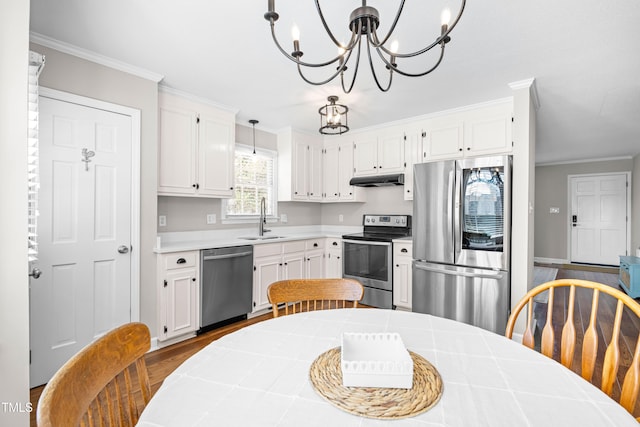 kitchen featuring white cabinets, hanging light fixtures, stainless steel appliances, light countertops, and a sink