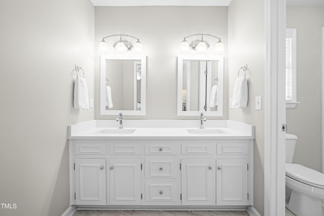 bathroom featuring toilet, double vanity, and a sink