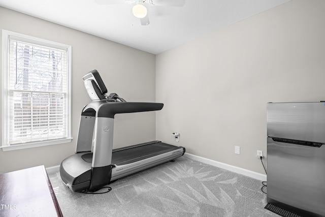 workout area featuring a ceiling fan, light colored carpet, and baseboards