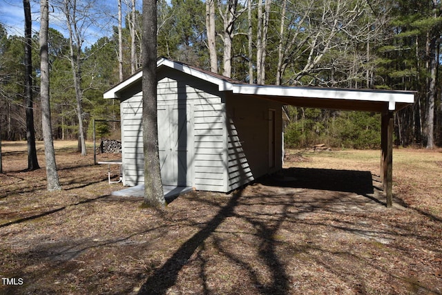 view of shed with a carport and a forest view